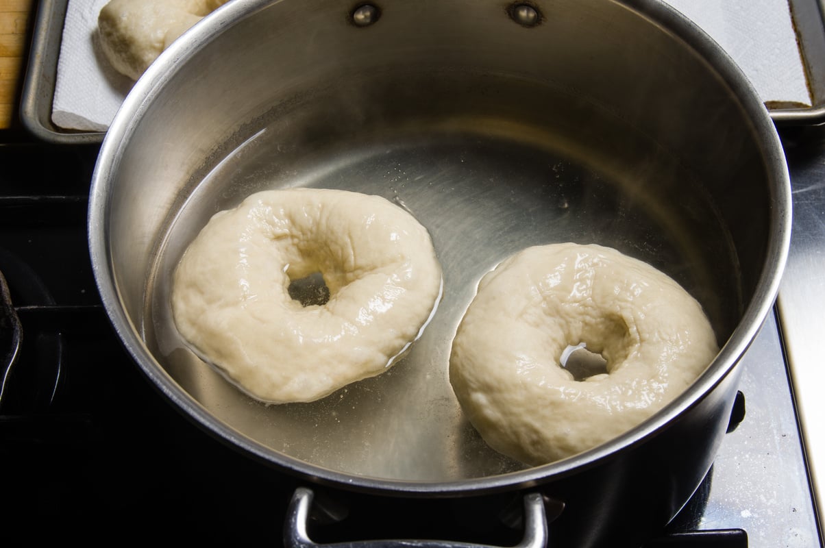 Fresh bagels being boiled before baking