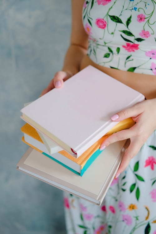 Female hands holding stack of paper books. Woman self-development concept.